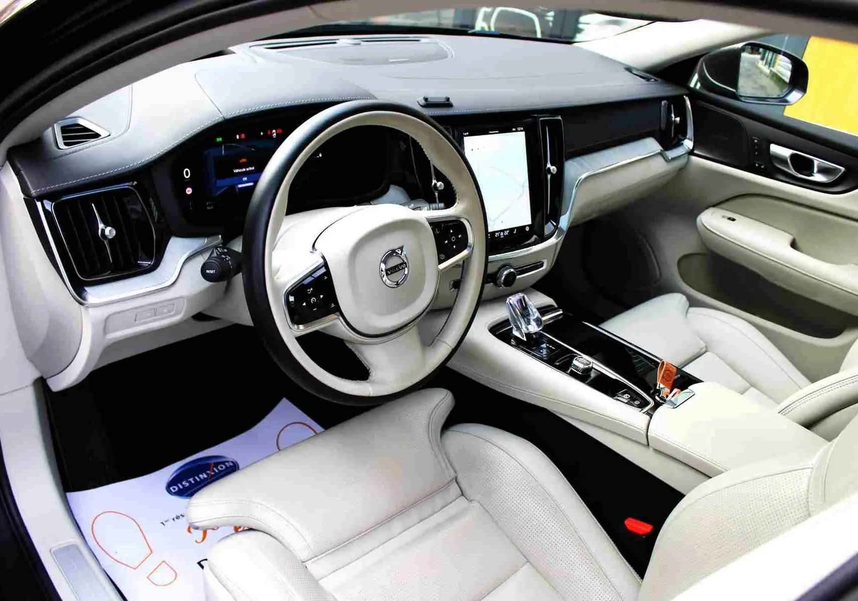 Intérieur clair du Volvo S60 2024, vue côté conducteur, avec tableau de bord numérique et console centrale élégante.