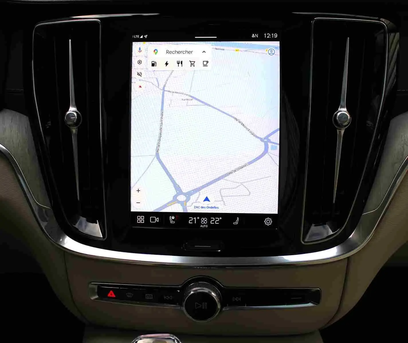 Écran tactile central avec navigation GPS dans l’habitacle beige d’un Volvo S60 gris métal 2024 hybride rechargeable.