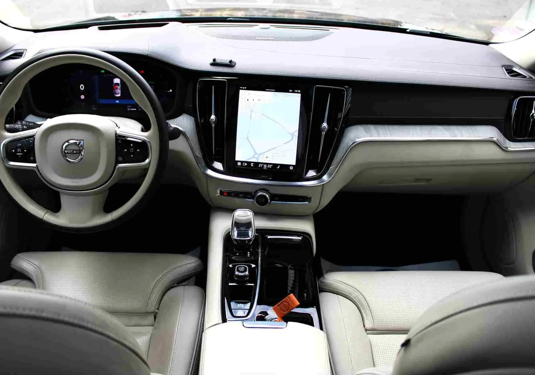 Intérieur clair de la Volvo S60 2024, vue du poste de conduite avec écran central tactile et volant multifonction.