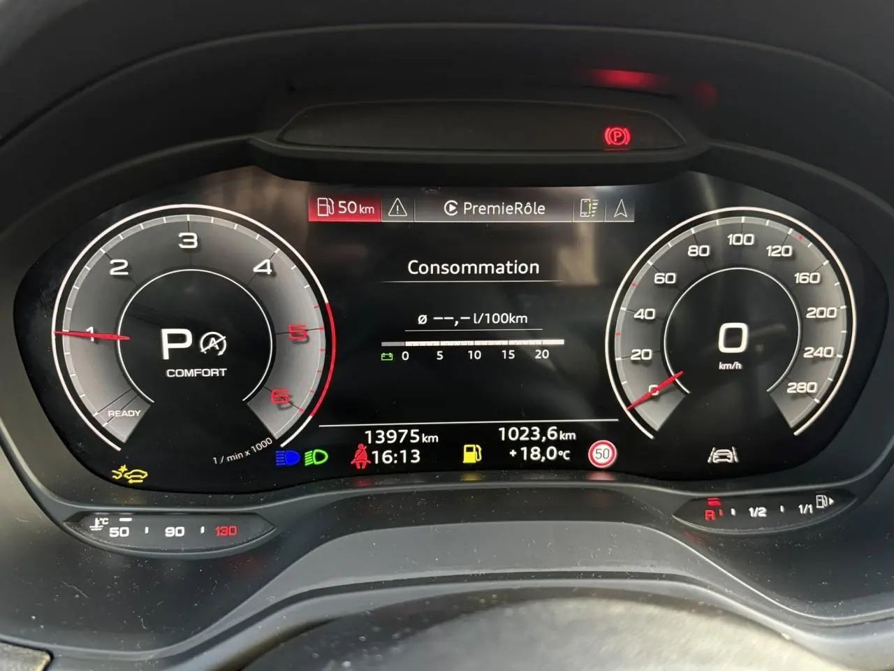 Vue rapprochée du tableau de bord numérique de l'Audi Q2 35 TDI 150 S-Tronic S-Line affichant la consommation et les compteurs.