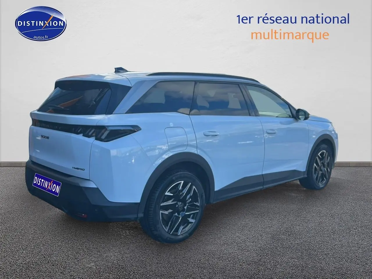 Vue 3/4 arrière droite du Peugeot 5008 Hybrid blanc okenite avec jantes alu et feux arrière LED noirs.