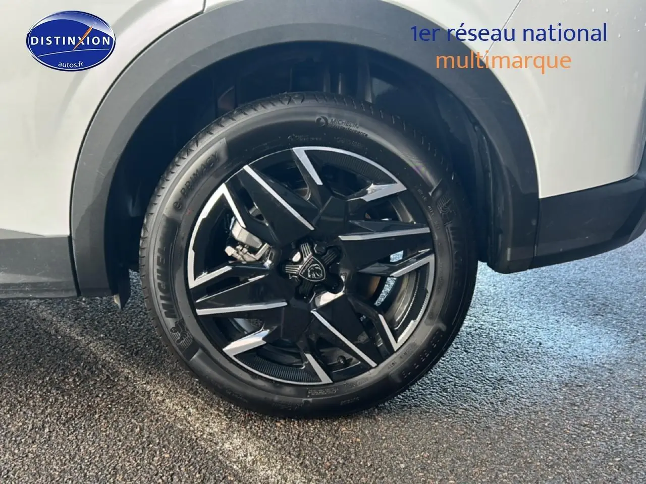 Gros plan sur la roue avant droite avec jante alu noire et argentée du Peugeot 5008 blanc okenite.