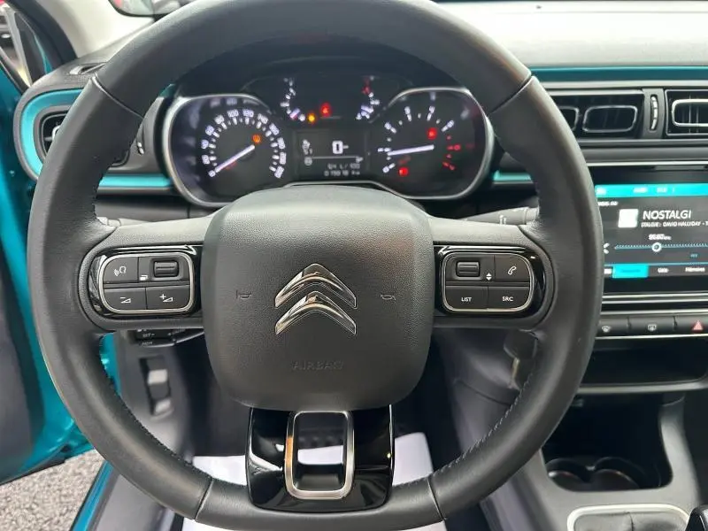 Vue intérieure centrée sur le volant noir de la Citroën C3 2023, avec tableau de bord et touches de bleu Spring Blue visibles.