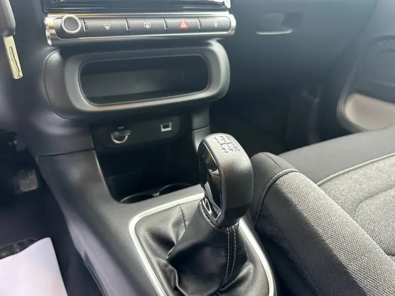 Gros plan sur le levier de vitesses manuel noir et la console centrale de la Citroën C3 2023, intérieur gris Mica Grey.