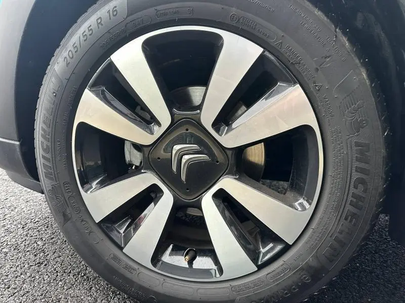 Gros plan sur la jante alu noire et argentée d'une Citroën C3 2023 Spring Blue avec logo Citroën au centre.