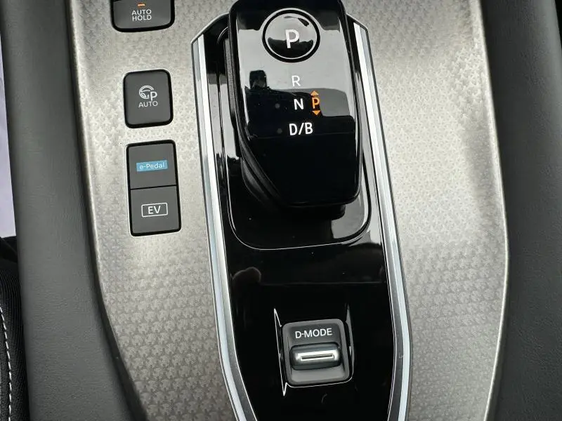 Gros plan sur la console centrale du Nissan Qashqai Hybrid e-POWER 2025, avec levier de vitesse et boutons de mode de conduite.