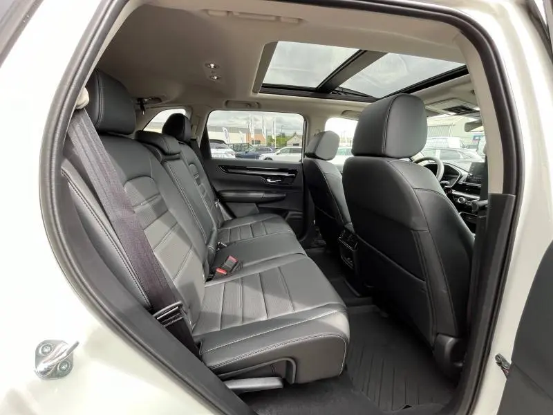 Vue intérieure côté gauche du Honda CR-V 2024 blanc Platine nacrée, montrant les sièges arrière en cuir noir et le toit panoramique.