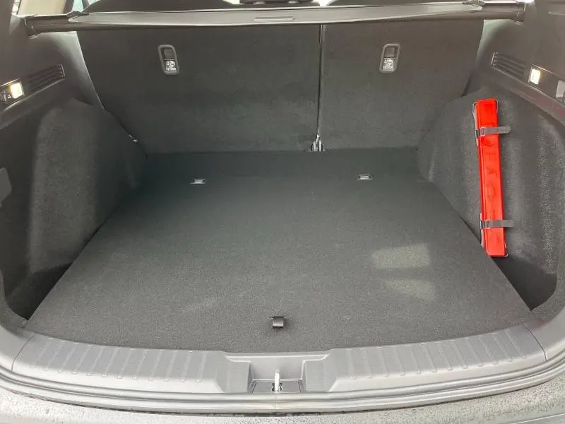 Coffre spacieux du Honda CR-V 2024 vu de face, avec tapis noir et triangle de sécurité rouge fixé sur le côté droit.