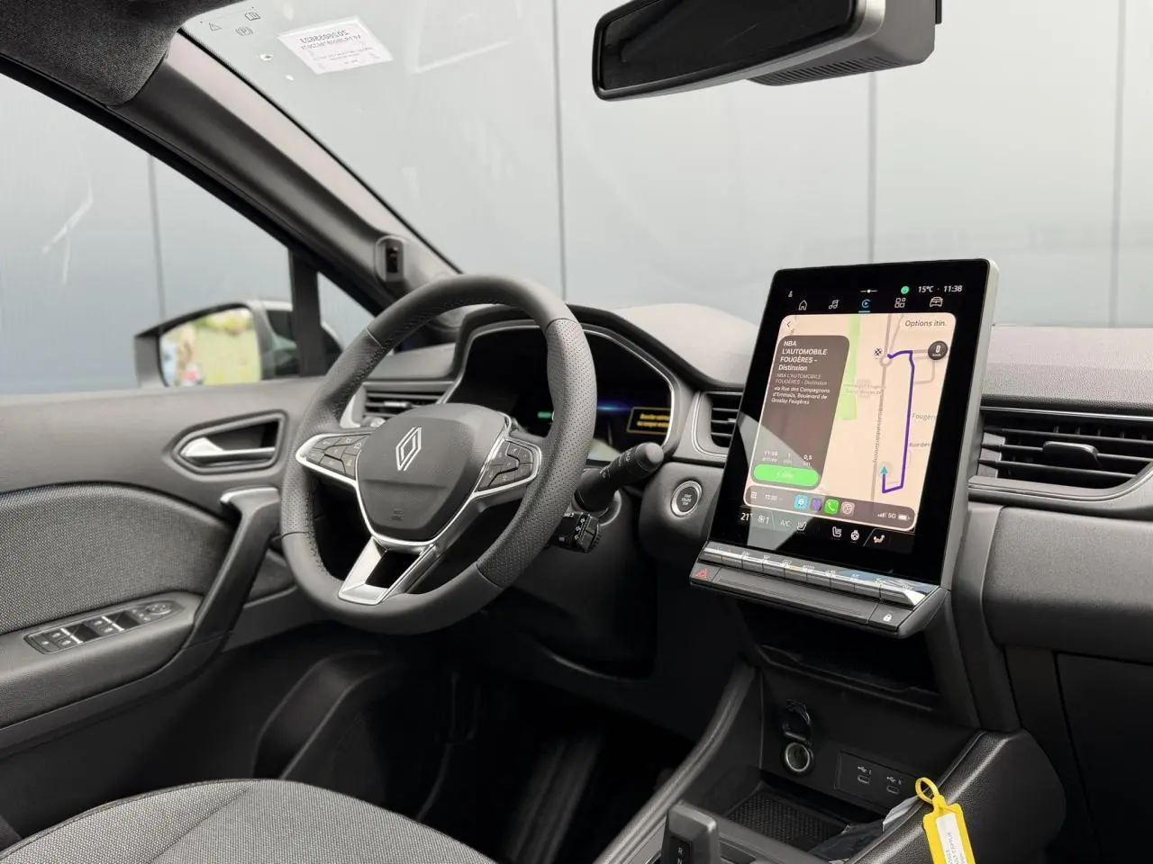 Vue intérieure côté conducteur du Renault Captur bleu, avec volant multifonction et écran tactile vertical central allumé.