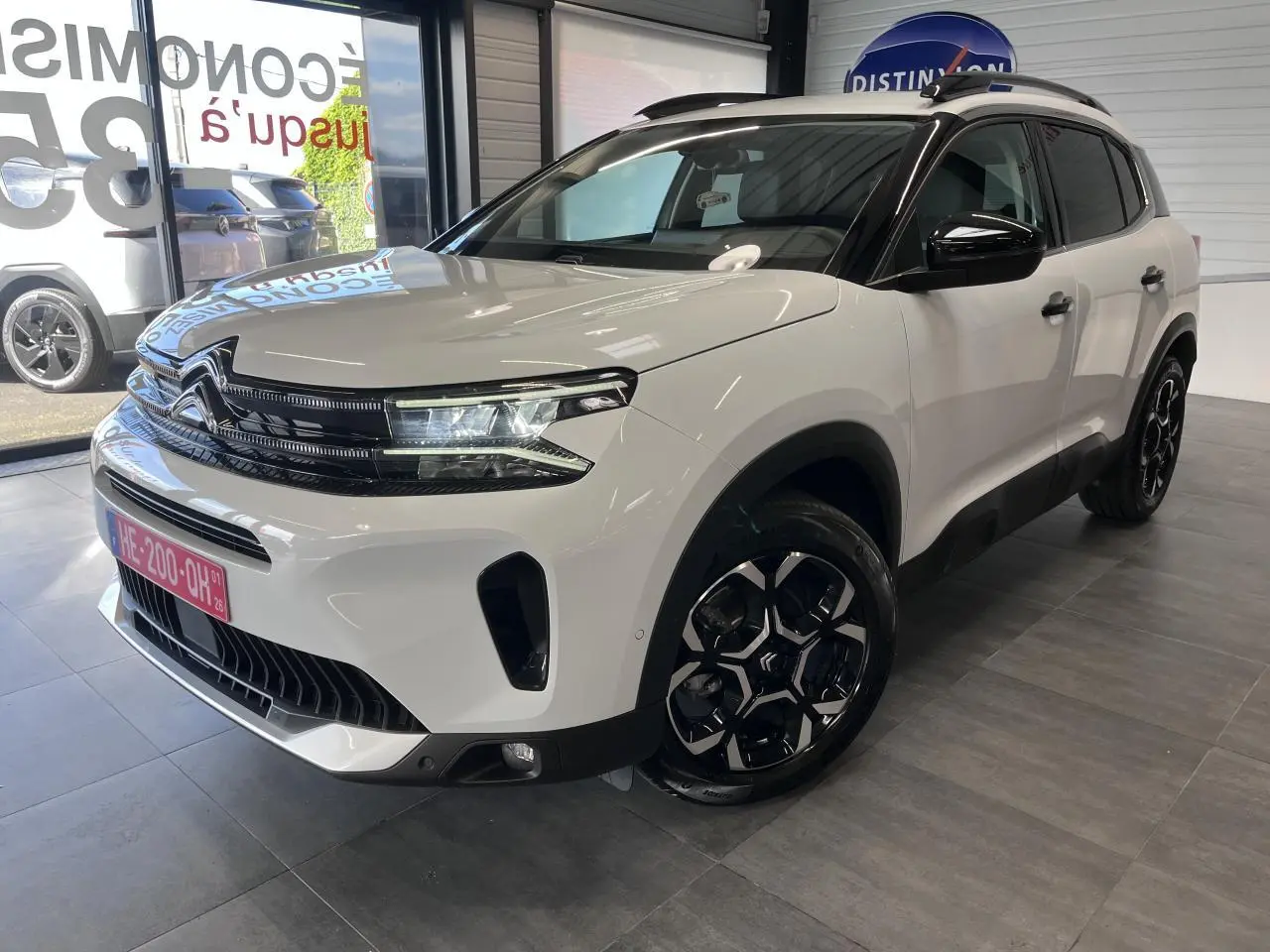 Vue 3/4 avant droite d'un Citroën C5 Aircross blanc nacré avec calandre noire brillante et jantes alliage bi-ton.