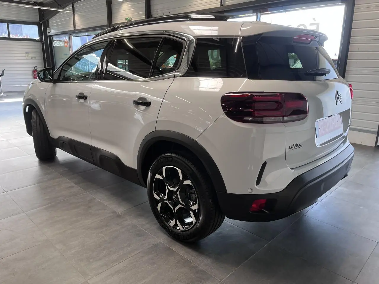 Vue 3/4 arrière droite d’un Citroën C5 Aircross blanc nacré avec jantes alliage bi-ton et vitres surteintées.