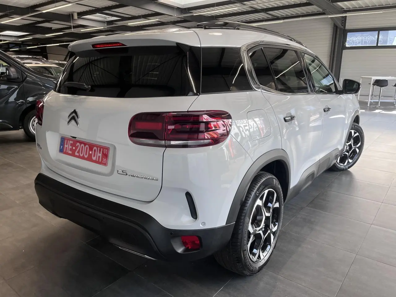 Vue 3/4 arrière droit d'un Citroën C5 Aircross blanc nacré avec jantes alliage bi-ton et vitres teintées.