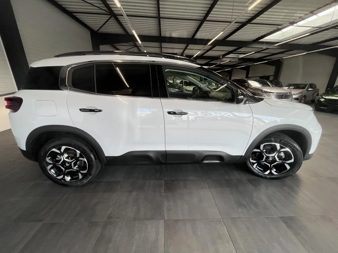Vue de profil côté gauche d'un Citroën C5 Aircross blanc nacré avec jantes alliage bi-ton et vitres surteintées.