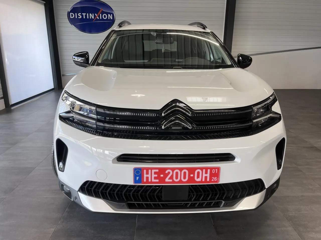 Vue avant d'un Citroën C5 Aircross blanc nacré avec calandre noire brillante et plaques rouges temporaires.