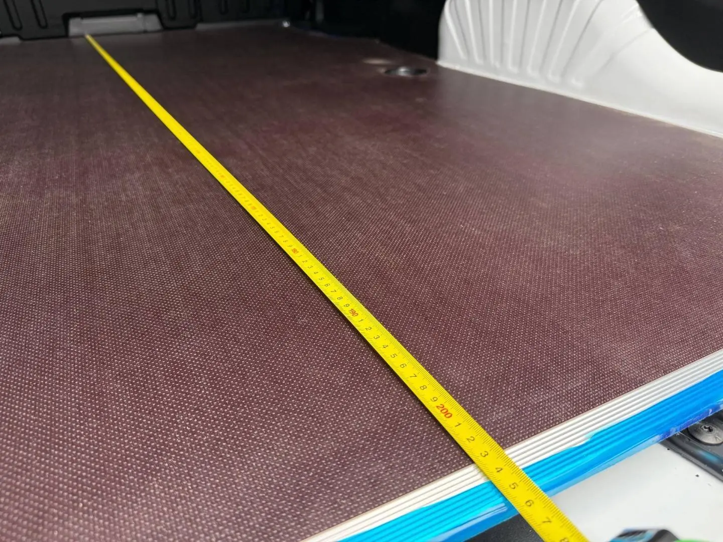 Vue rapprochée de la zone de chargement du Citroën Berlingo Fourgon XL Diesel blanc Icy avec un mètre jaune étalé.