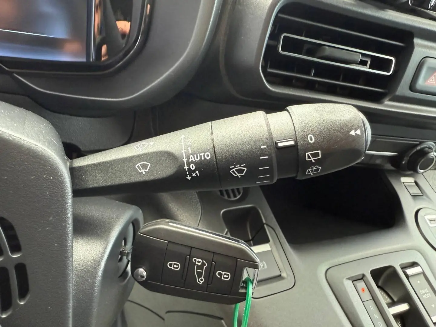 Gros plan intérieur sur la commande d’essuie-glace et la clé insérée dans le contacteur d’un Citroën Berlingo Fourgon blanc.