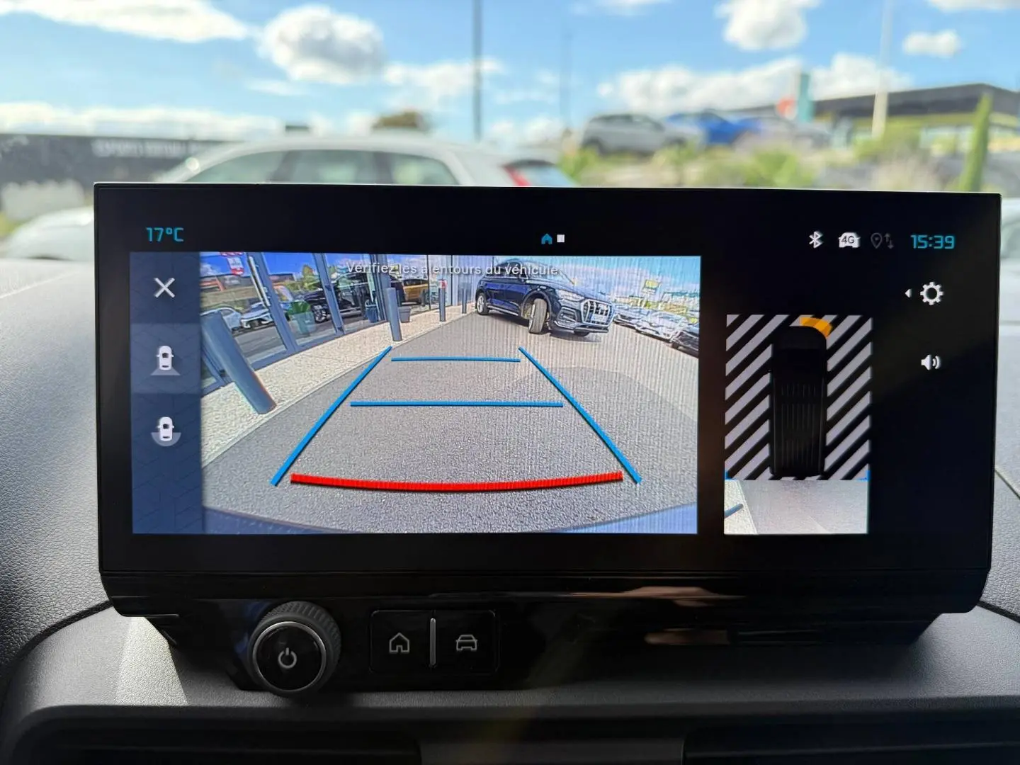 Écran intérieur du Citroën Berlingo Fourgon XL Diesel blanc, affichant la caméra de recul avec lignes de guidage en bleu et rouge.