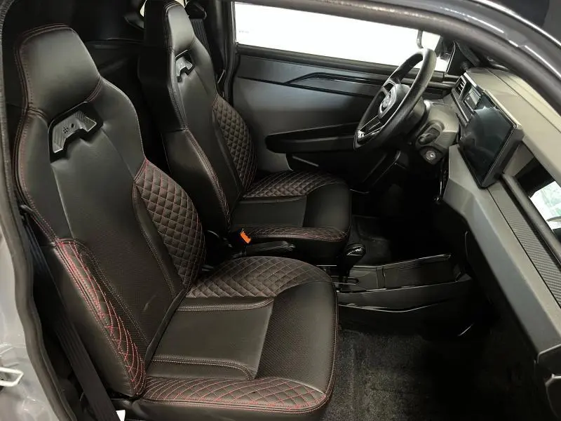 Vue intérieure côté conducteur de la LIGIER JS50 SPORT ULTIMATE E5+ 2025 avec sièges noirs matelassés et surpiqûres rouges.