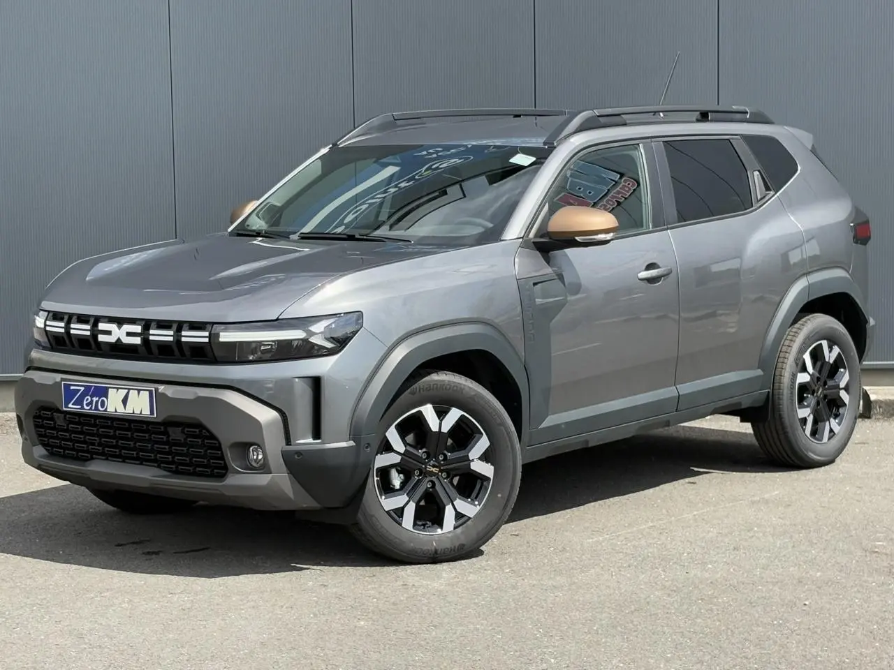 Vue 3/4 avant droite du Dacia Duster gris schiste avec coques de rétroviseurs brun cuivré et jantes alliage 17 pouces.