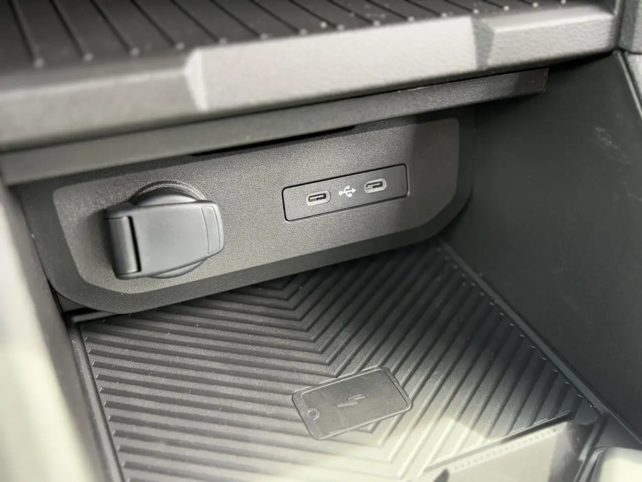 Gros plan sur la console centrale du Dacia Duster 2025 gris avec ports USB-C et zone de charge sans fil.