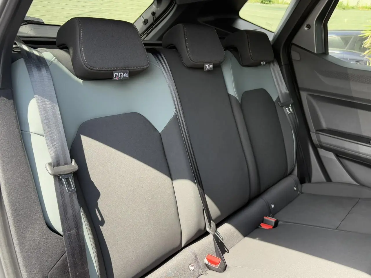 Vue latérale des sièges arrière gris clair et noir du Dacia Duster 2025 avec ceintures de sécurité visibles.