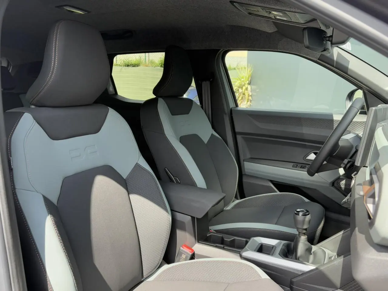 Intérieur du Dacia Duster 2025, vue côté droit sur sièges TEP bicolores gris et noir avec console centrale et levier manuel.