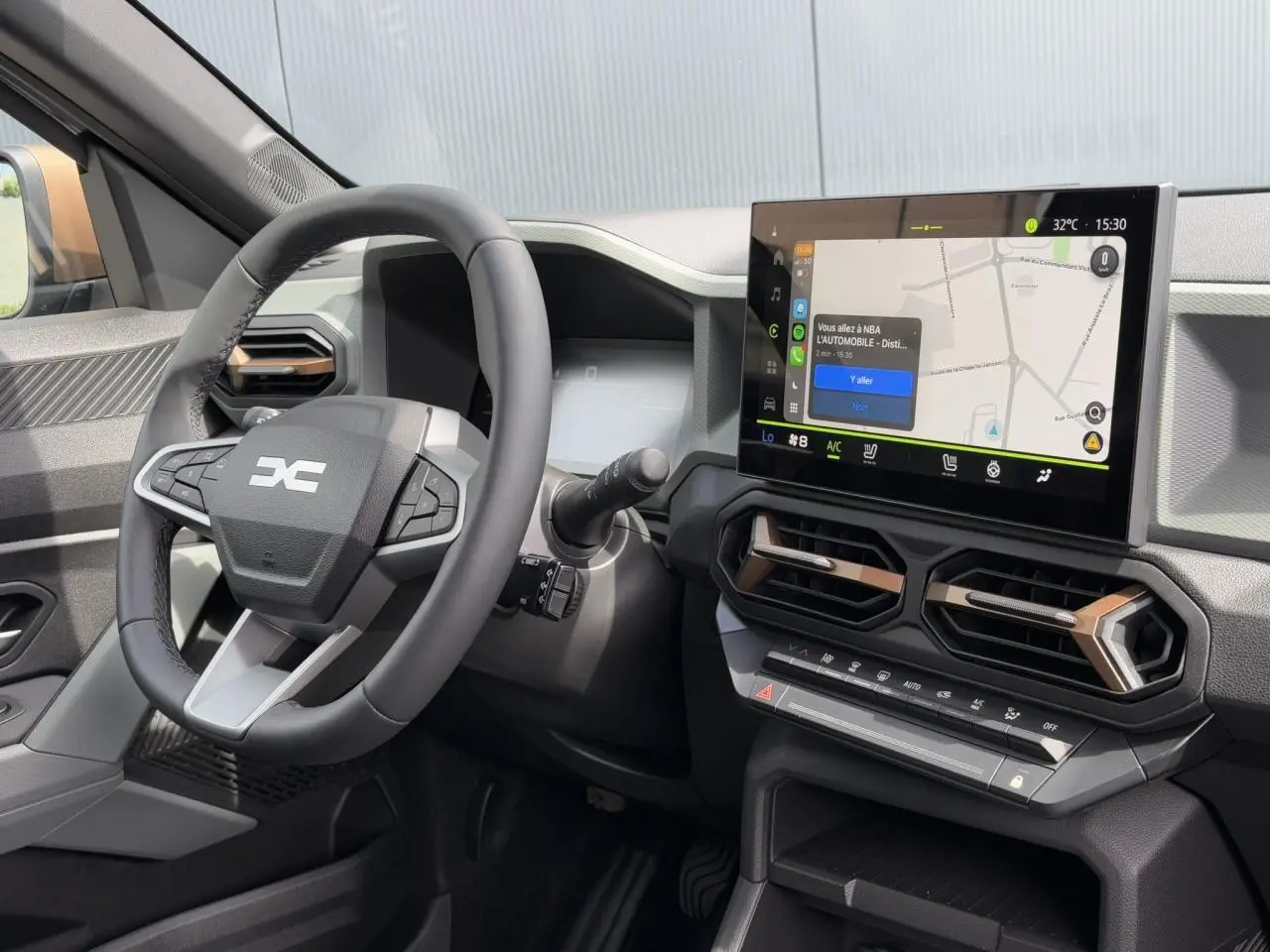 Vue intérieure du tableau de bord du Dacia Duster 2025 avec écran tactile GPS 10 pouces et volant multifonction noir.