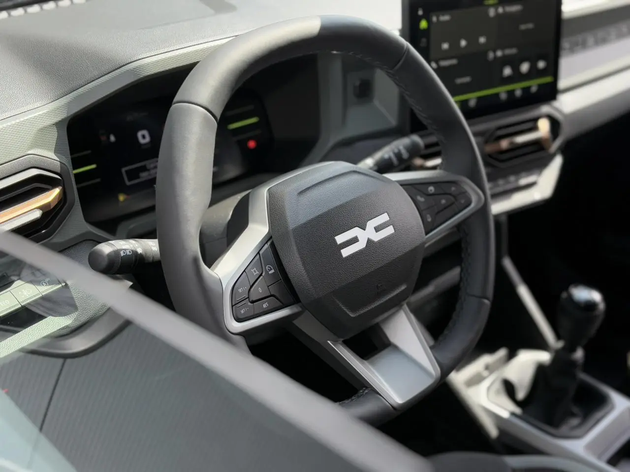 Gros plan sur le volant multifonction noir et la console centrale du Dacia Duster TCE 4X2 2025.