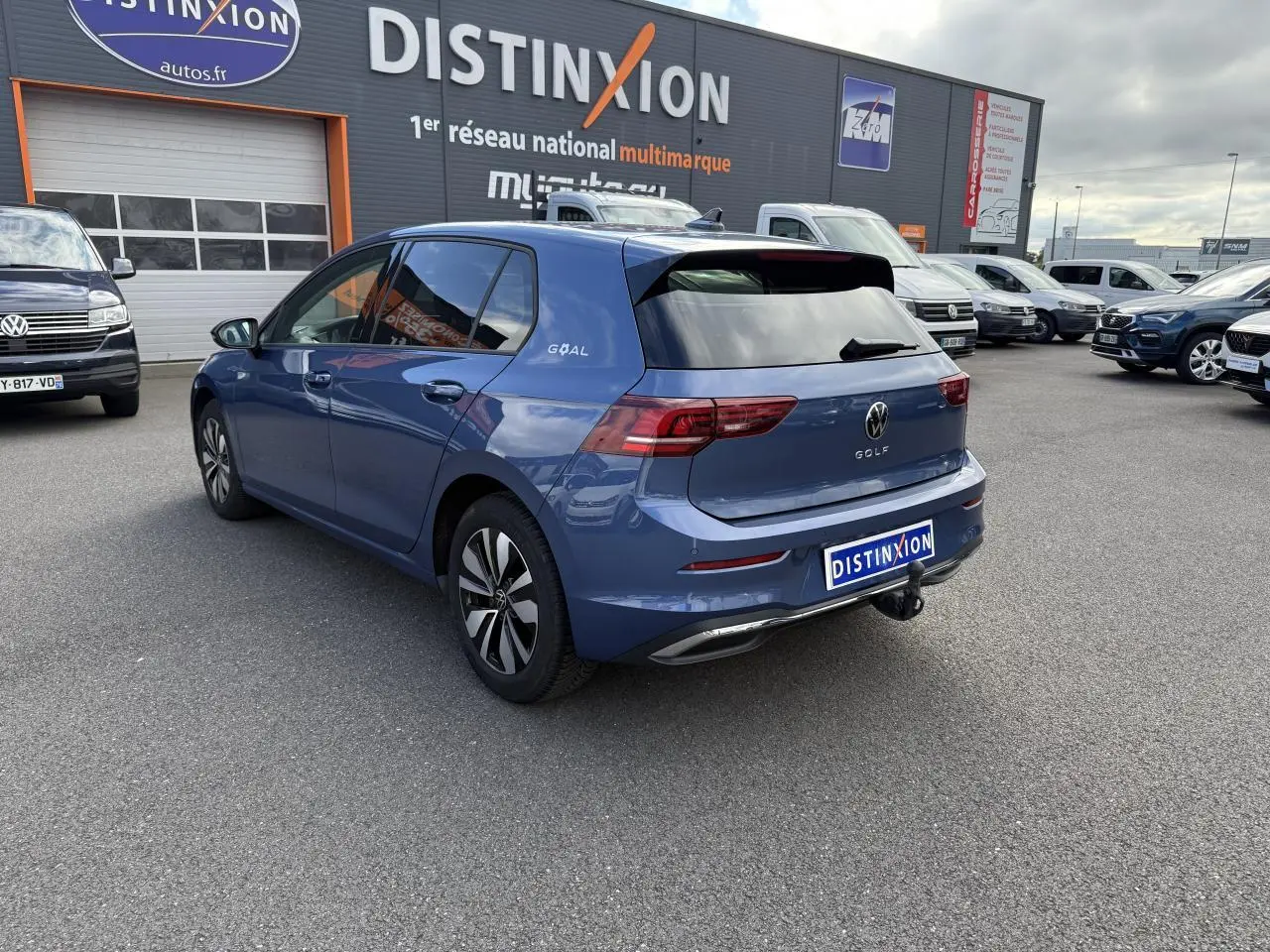 Vue 3/4 arrière droite d'une Volkswagen Golf 8 bleue anémone métallisée avec attelage escamotable et vitres surteintées.