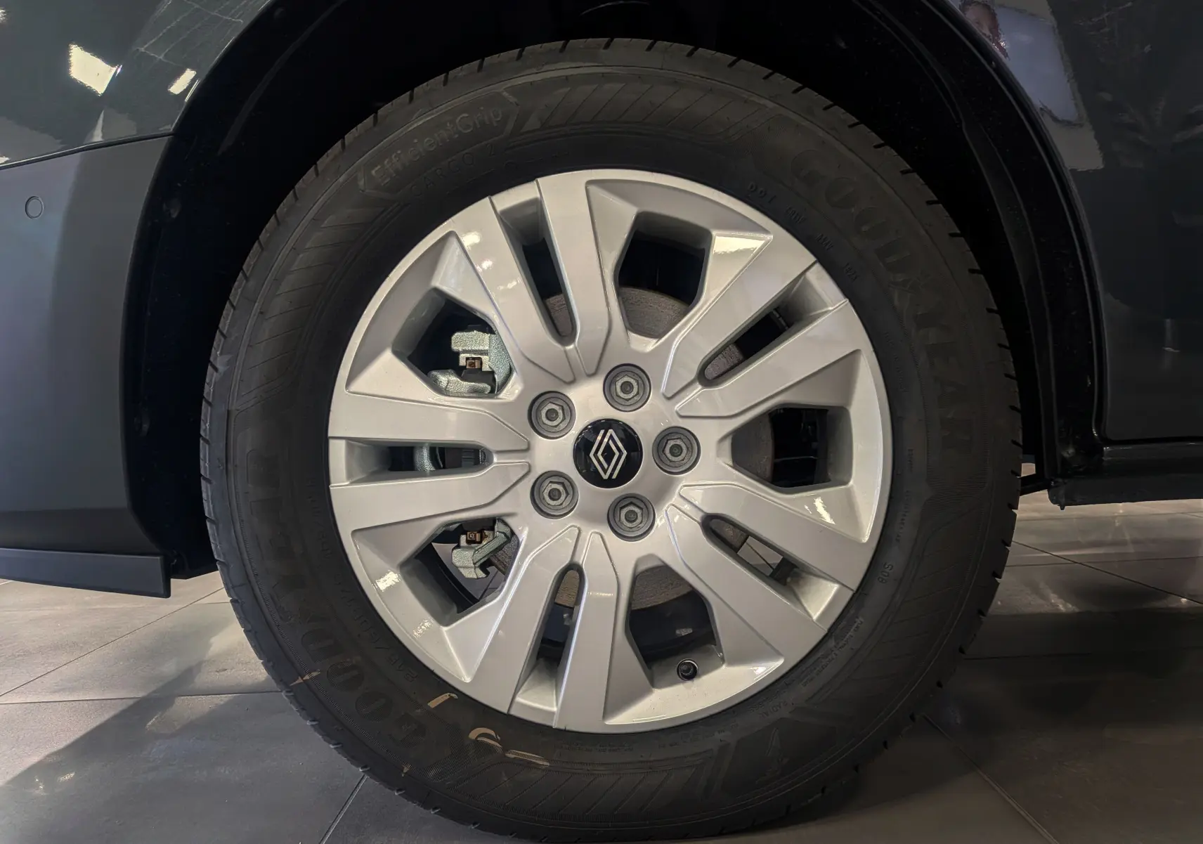 Gros plan sur la roue avant gauche du Renault Trafic Combi gris Comète avec jante alliage et logo Renault central.