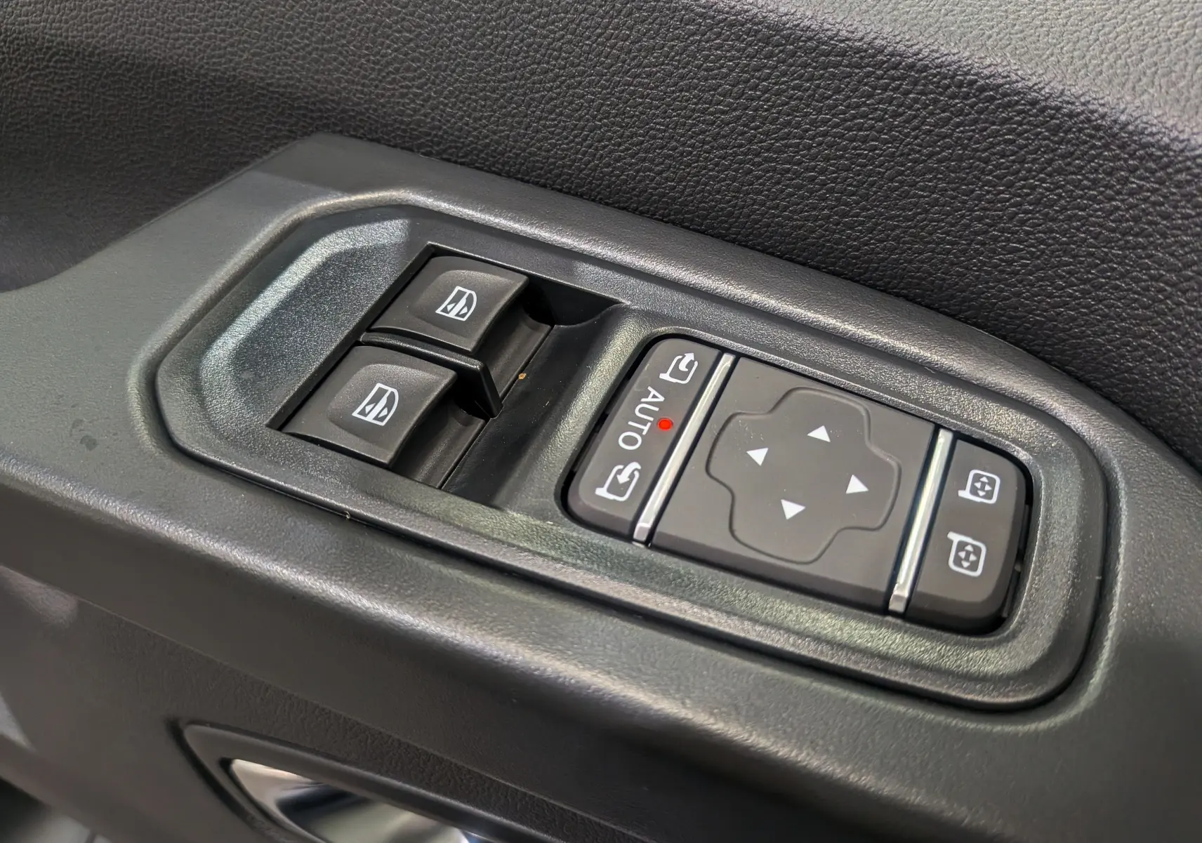 Gros plan sur les commandes de lève-vitres et réglage des rétroviseurs côté conducteur du Renault Trafic Combi gris Comète 2025.