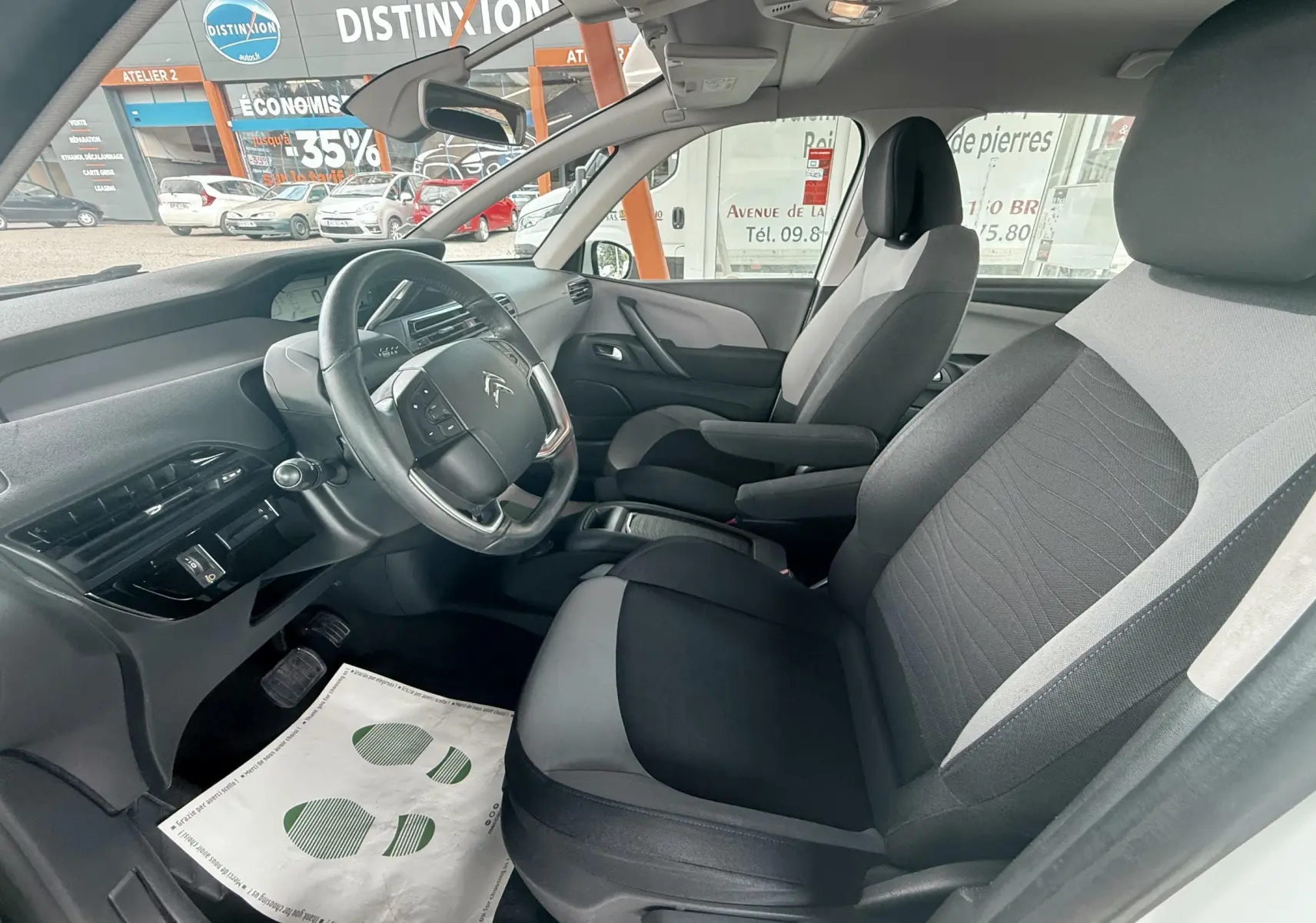 Intérieur avant droit du Citroën C4 Picasso blanc 2014, montrant sièges tissu bicolore et tableau de bord moderne.