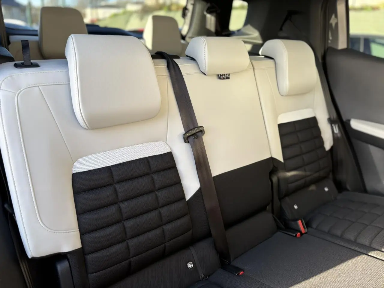 Vue rapprochée des sièges arrière bicolores noir et gris clair du Citroën C3 Aircross Hybrid 2025 en configuration 7 places.