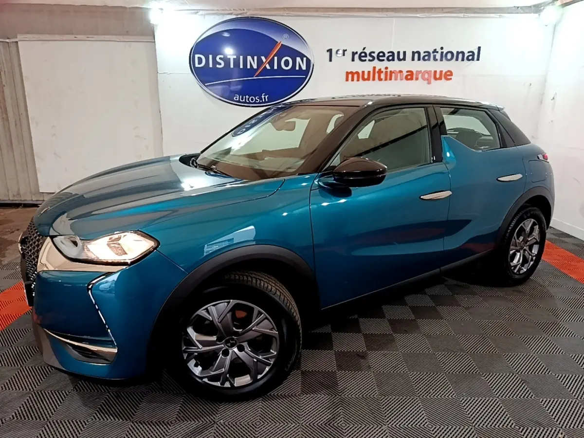 Vue 3/4 avant droit d'un DS3 Crossback bleu métallisé avec toit noir et jantes alliage en showroom.