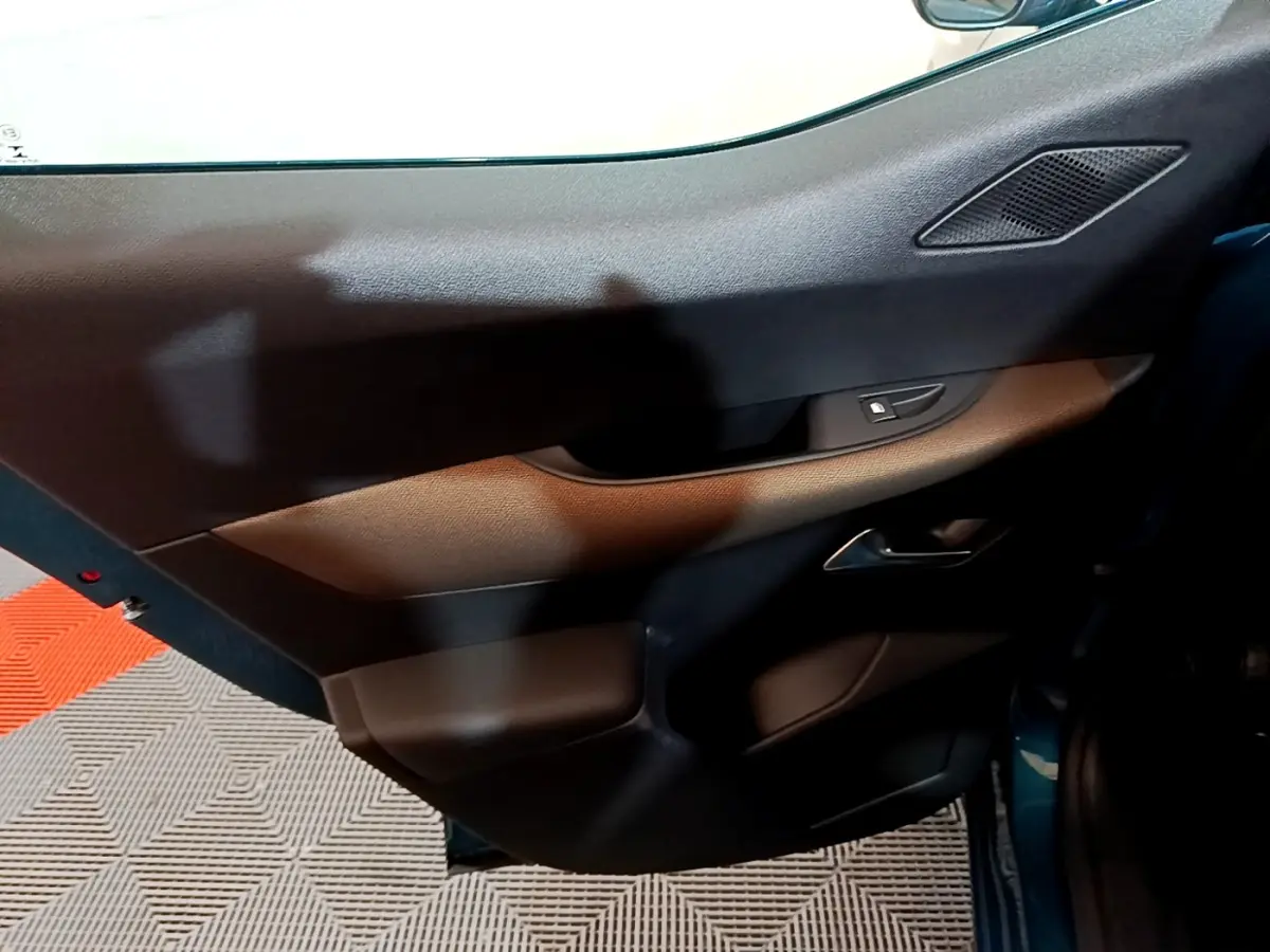 Vue intérieure du panneau de porte côté droit du DS3 Crossback bleu, avec commandes de vitre et haut-parleur intégré.