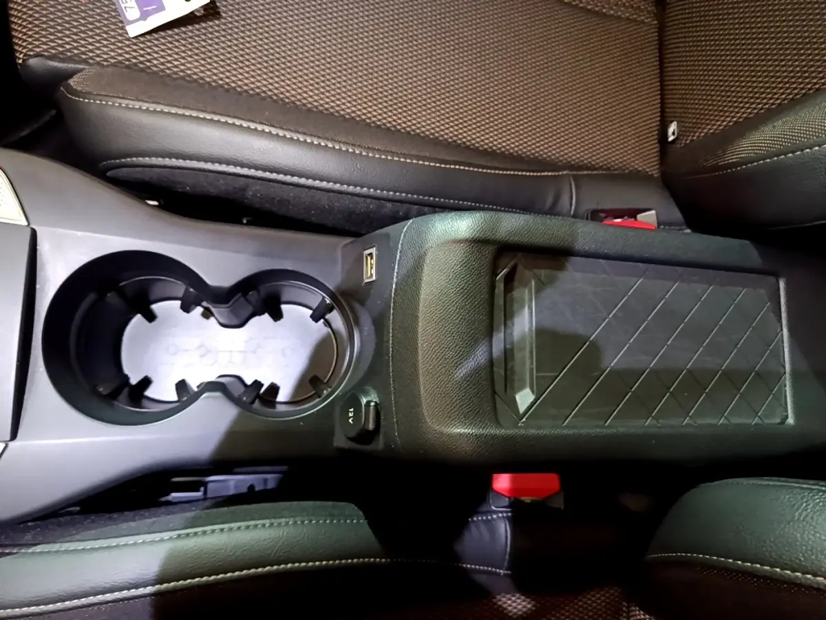 Vue plongeante sur la console centrale noire du DS3 Crossback bleu, avec porte-gobelets et accoudoir à motif géométrique.