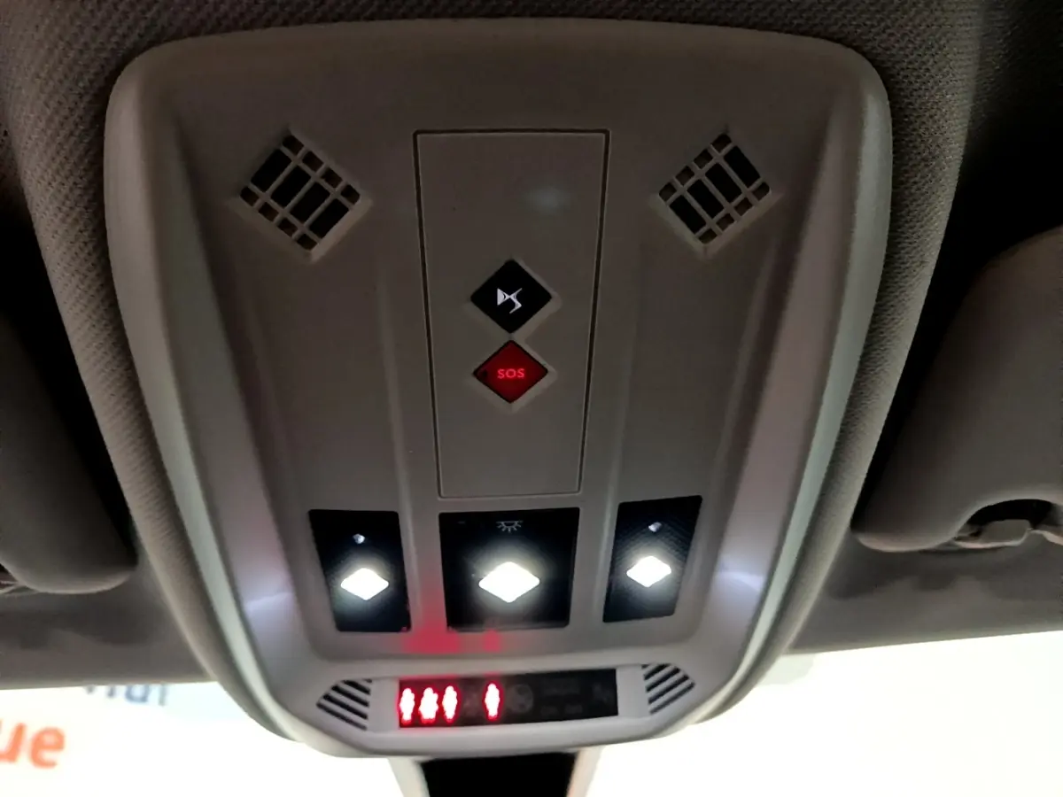 Vue en contre-plongée du plafonnier intérieur gris du DS3 Crossback bleu avec boutons SOS et éclairages LED allumés.