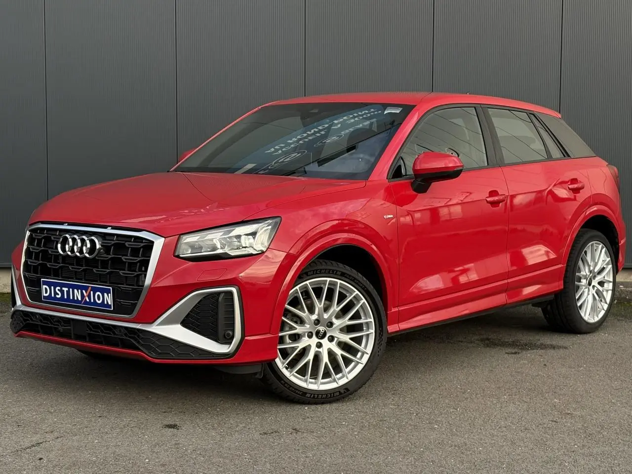 Audi Q2 35 TDI S-Line rouge vue 3/4 avant droit, avec jantes alliage et calandre noire distinctive.
