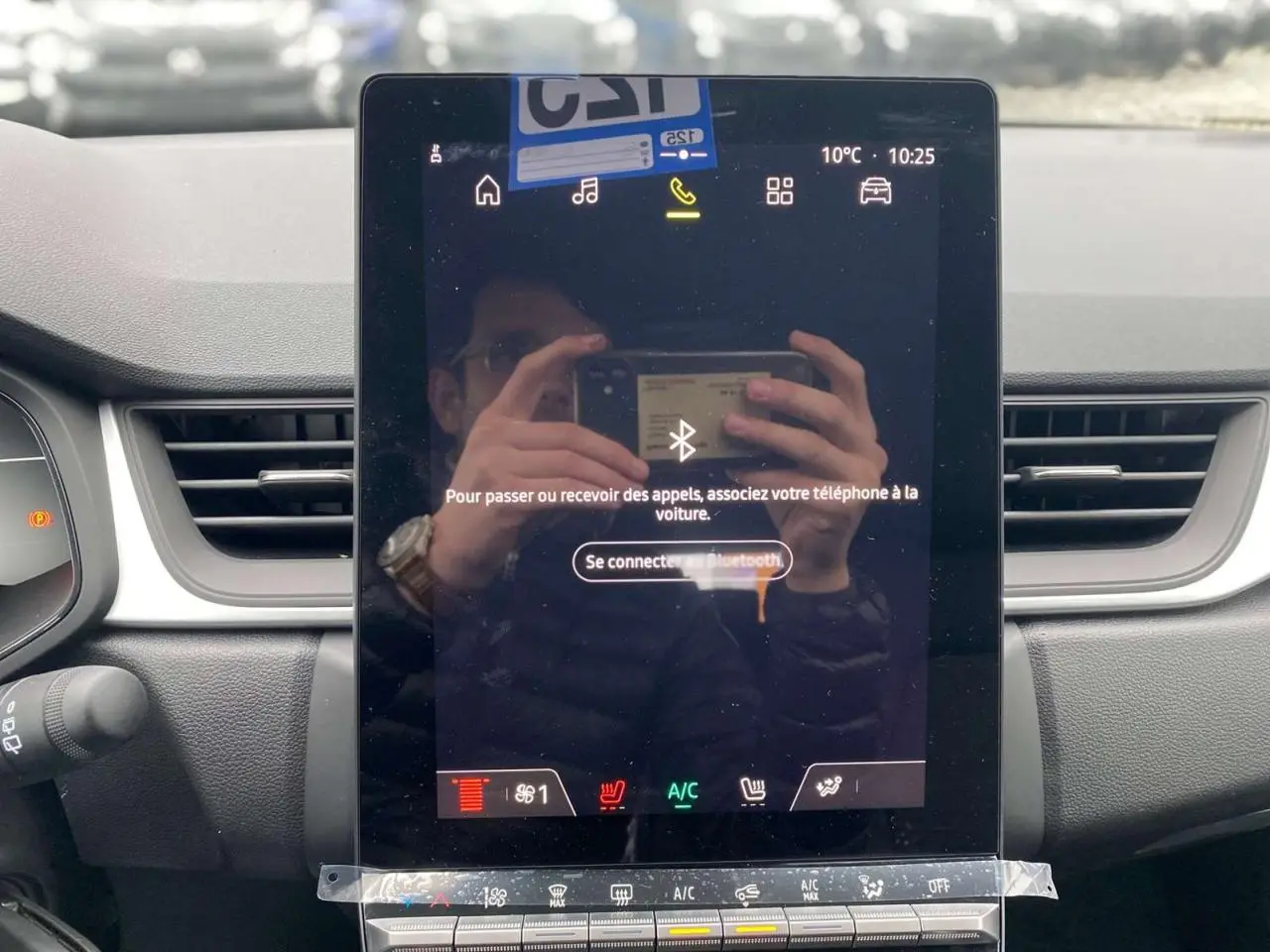 Vue rapprochée de l'écran tactile central du tableau de bord du Renault Captur 2025 avec commandes climatisation et ventilation visibles.