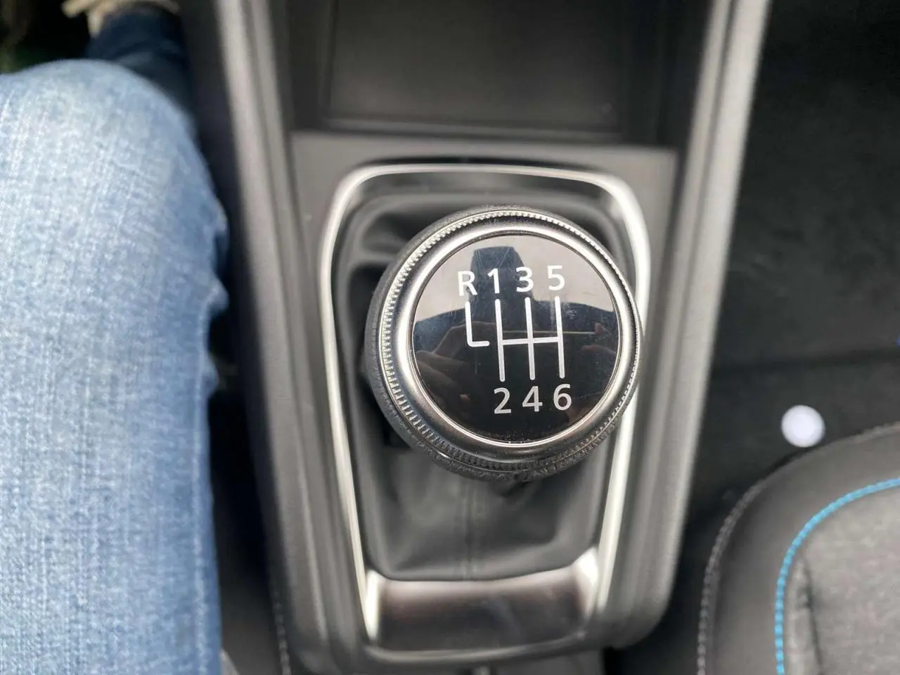 Gros plan sur le levier de vitesses manuel du Renault Captur noir étoilé, avec couture bleue visible sur le siège adjacent.