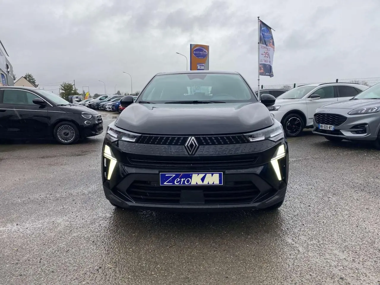 Vue de face du Renault Captur 2025 noir étoilé avec feux LED allumés sur parking humide.
