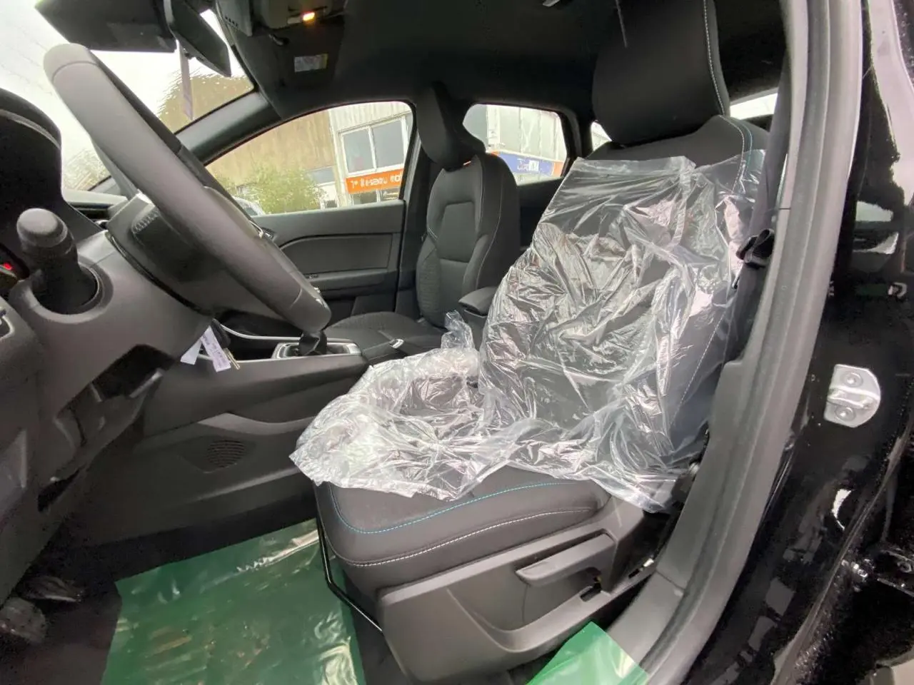 Vue intérieure côté conducteur du Renault Captur noir étoilé 2025, siège avant protégé par une housse plastique.