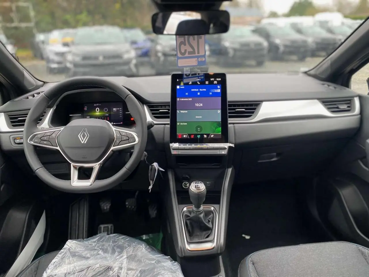 Vue intérieure frontale du Renault Captur 2025 avec volant, écran tactile vertical et levier de vitesses manuel visible.