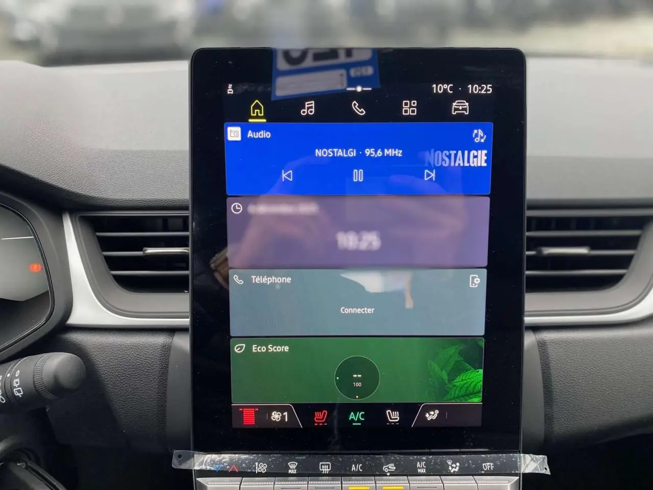 Écran tactile central du tableau de bord du Renault Captur 2025, affichant radio et climatisation, intérieur noir.