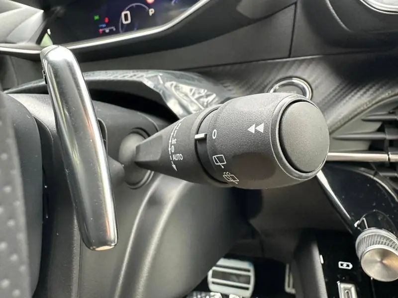 Gros plan sur la commande des essuie-glaces à gauche du volant dans l’habitacle gris du Peugeot 2008 Hybrid 2025.