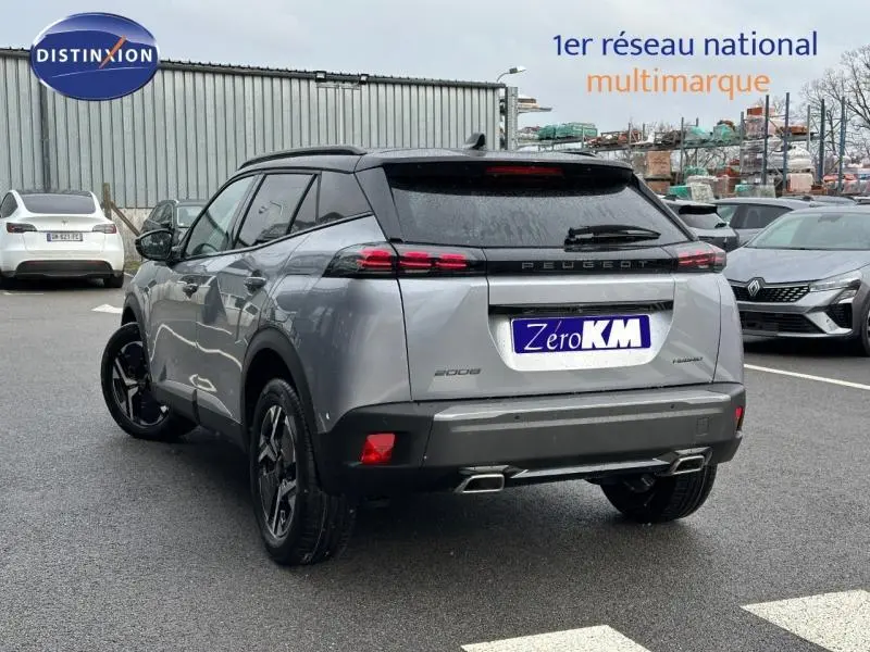 Vue 3/4 arrière d’un Peugeot 2008 gris 2025 hybride avec feux arrière LED et double sortie d’échappement chromée.