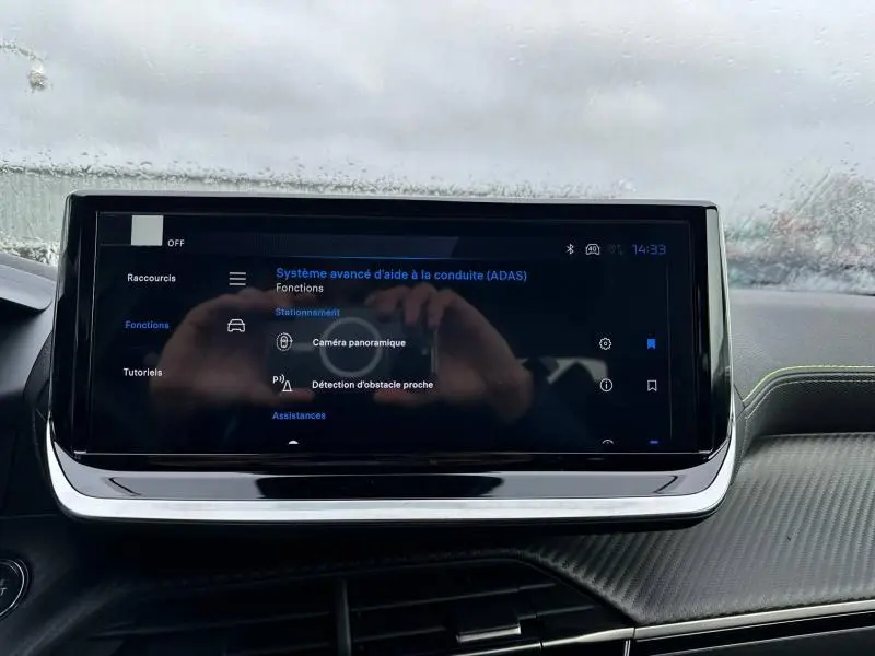Écran tactile central du tableau de bord du Peugeot 2008 gris 2025 affichant les aides à la conduite avancées.