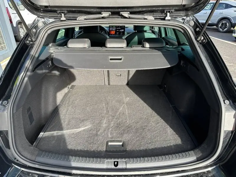 Coffre ouvert vu de l'arrière du SEAT LEON ST 2025 noir minuit métallisé, montrant l'espace de chargement et la tablette de séparation.