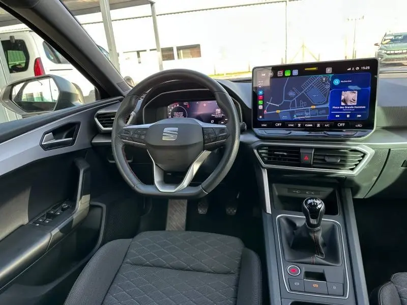 Vue intérieure avant du SEAT LEON ST 1.5 eTSI Hybrid 2025, tableau de bord moderne avec écran tactile et volant multifonction.