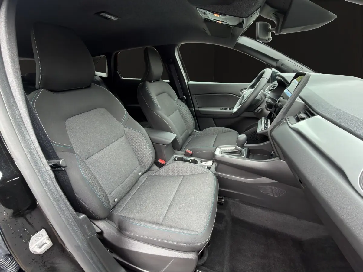 Vue intérieure côté conducteur de la Renault SYMBIOZ 2025, sièges tissu gris avec surpiqûres bleues et tableau de bord moderne.